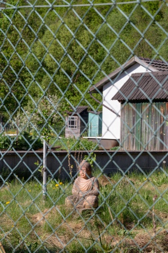 Buddha hinter bayerischem Gartenzaun